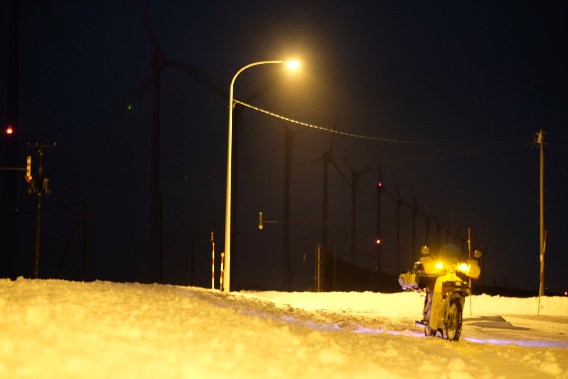 風力発電の風車と雪道の夜間走行